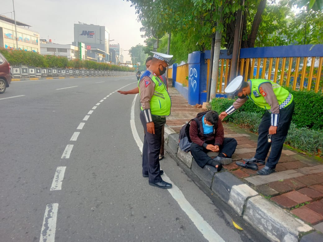 Petugas Satlantas Jakarta Barat membantu seorang pengendara sepeda motor yang tiba tiba mengalami pingsan disekitar Tl tomang