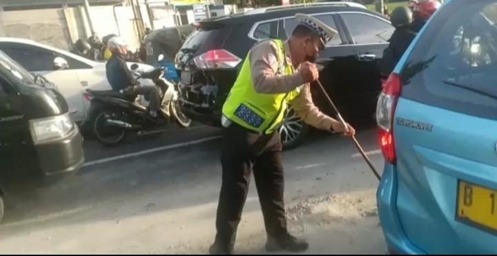 Personel Sat Lantas Jakarta Barat Membersihkan Kerikil Tumpahan Kendaraan Molen Untuk Menghindari Resiko Laka Lantas