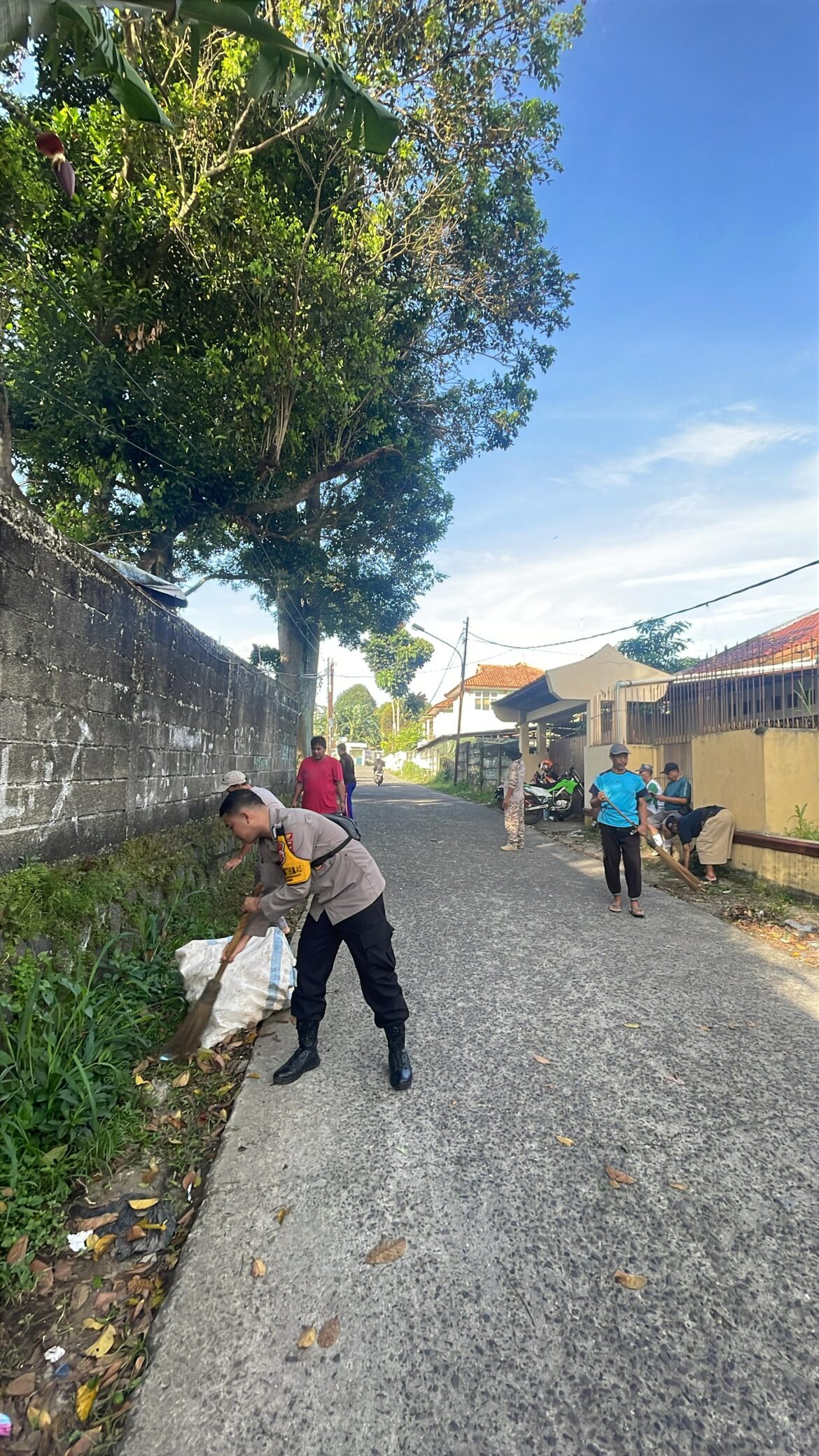 Bhabinkamtibmas Polsek CWI Polres Bogor gotong royong bersama warga Desa Banjarwangi memberaihkan jalan lingkungan